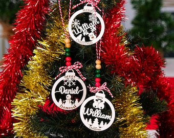 May include: Three white wooden Christmas ornaments with red and white twine, red and white beads, and green and white beads. The ornaments are decorated with snowflakes and the words "Merry Christmas". The ornaments are personalized with the names "William", "Daniel", and "William".
