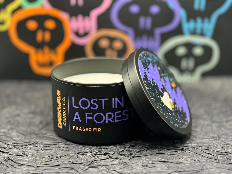 May include: A black candle jar with a white lid. The candle jar has a black label with white text that reads 'DARKWAVE CANDLE CO. LOST IN A FOREST FRASER FIR'.
