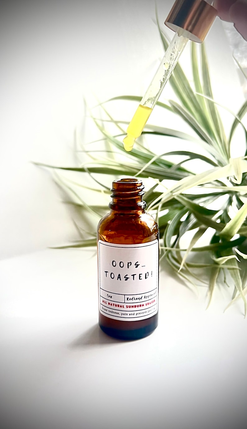 May include: A brown glass bottle with a white label that reads "Oops... Toasted!"  Redhand Approved. All Natural Sunburn Eraser. Ease redness, pain and prevent future sun damage.  The bottle has a dropper with a yellow liquid.