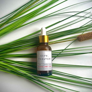 May include: A brown glass bottle with a gold cap and a white label that reads "OOPS...TOASTED!"  All Natural Sunburn Eraser.  Redhead Approved.