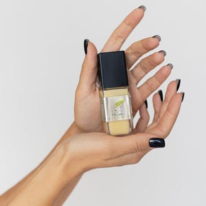 Hand holding vegan aloe vera serum bottle, clean skincare product.