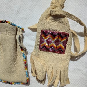 Puede incluir: Dos bolsas de cuero hechas a mano. Una es una bolsa peque&ntilde;a con ribete de cuentas de colores. La otra es una bolsa m&aacute;s grande con un dise&ntilde;o geom&eacute;trico de cuentas en tonos rojos, amarillos y naranjas. La bolsa m&aacute;s grande tiene flecos.