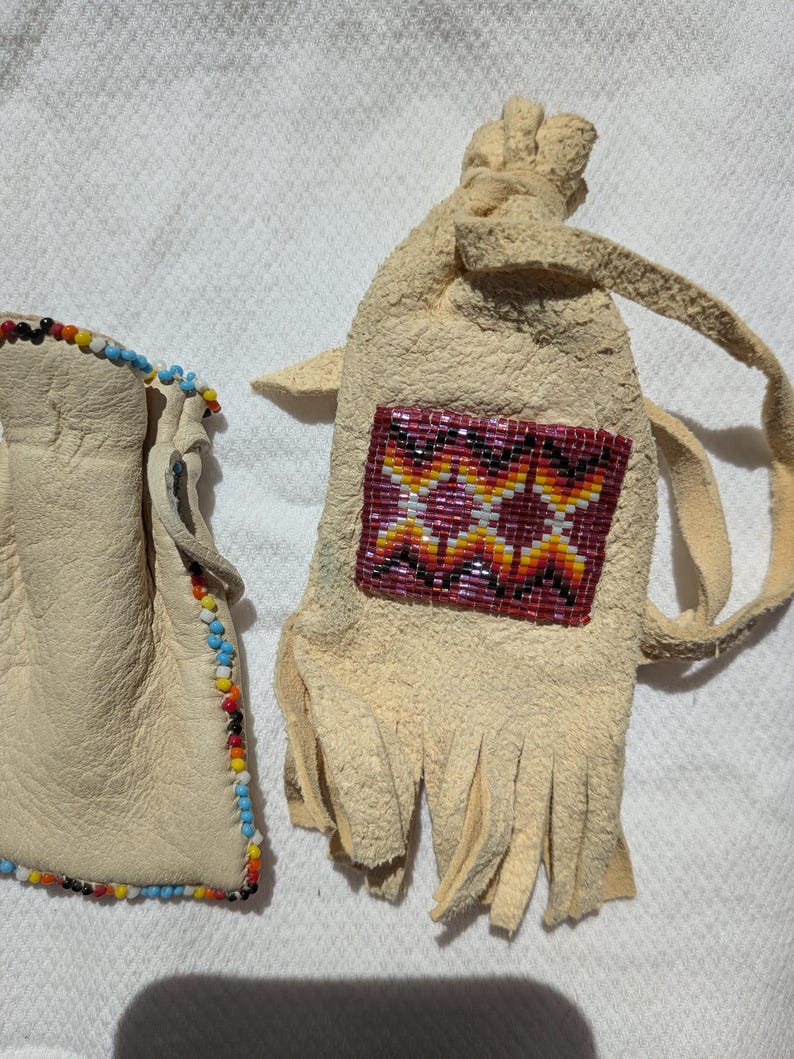 Puede incluir: Dos bolsas de cuero hechas a mano. Una es una bolsa peque&ntilde;a con ribete de cuentas de colores. La otra es una bolsa m&aacute;s grande con un dise&ntilde;o geom&eacute;trico de cuentas en tonos rojos, amarillos y naranjas. La bolsa m&aacute;s grande tiene flecos.