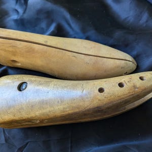 Può includere: Due stiracalzature in legno con meccanismi a molla in metallo. Gli stiracalzature sono marroni e hanno una finitura liscia e lucida.