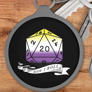 May include: A black and white keychain with a grey metal ring. The keychain features a 20-sided die with yellow, purple, and white stripes. The die is surrounded by a banner that reads "How I Roll".