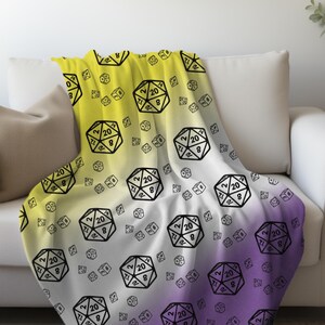 May include: A soft, yellow, white, and purple fleece throw blanket with a repeating pattern of black 20-sided dice.