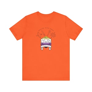 May include: Orange t-shirt with a graphic of a 20-sided die with a purple, yellow, and white color scheme. The die is surrounded by a bow and arrow, a sword, and a magic staff. The text "Rollin' with them Wedding Party" is below the die.