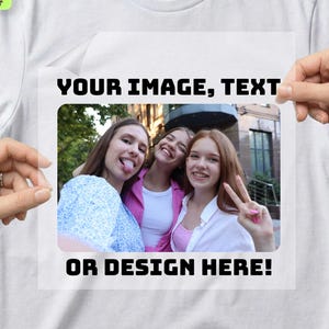 May include: White t-shirt with a rectangular design area featuring the text "YOUR IMAGE, TEXT OR DESIGN HERE!". The design area contains a photo of three smiling women. Additional text includes "IRON-ON DTF DECAL".