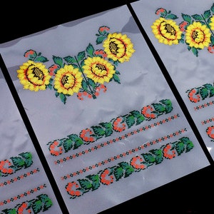 May include: Three clear plastic sheets with embroidered sunflower designs and the text "Слава Україні" in Ukrainian. The sunflowers are yellow with black centers and green leaves. The text is in green and red.