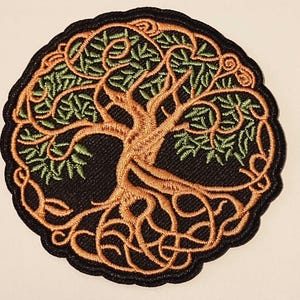 Op de afbeelding: Ronde geborduurde patch met een boomontwerp. De boom heeft bruine wortels en takken, groene bladeren en is geplaatst tegen een zwarte achtergrond. Het heeft een zwarte, geschulpte rand. Geschikt voor kleding.