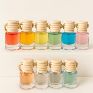 May include: A collection of small, clear glass bottles filled with colorful liquids. Each bottle has a wooden cap with a rope detail. The liquids are various colors, including red, yellow, green, blue, and pink.