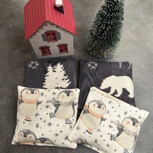 May include: Four decorative throw pillows with winter themes. Two pillows feature a grey and white woodgrain pattern with a pine tree and a polar bear. Two pillows feature a white background with a penguin ice skating pattern and snowflakes.
