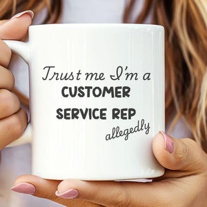 May include: White ceramic mug with black text that reads "Trust me I'm a customer service rep allegedly".