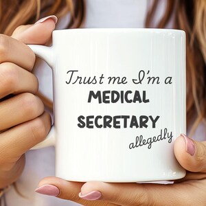 May include: White ceramic mug with black text that reads "Trust me I'm a Medical Secretary allegedly".
