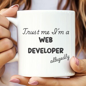 May include: White ceramic mug with black text that reads "Trust me I'm a WEB DEVELOPER allegedly".