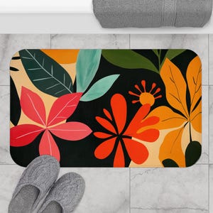 May include: A black bath mat with a colourful floral design. The design features red, orange, yellow, and green flowers on a black background.