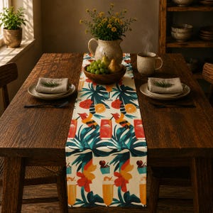 May include: A rectangular table runner featuring a repeating pattern of tropical leaves, orange slices, and various colorful cocktails in glasses. The design includes vibrant shades of green, orange, red, and yellow on a cream-colored background fabric.