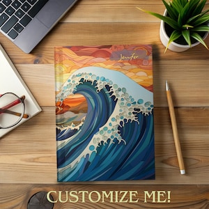 May include: A personalized notebook with a colorful illustration of a large wave crashing against a sunset background. The name "Jennifer" is written in gold lettering on the cover.