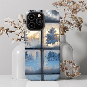 May include: A phone case with a wintery design. The case features a frosted window pane with intricate patterns of ice crystals. The background is a blurry image of a snowy landscape.