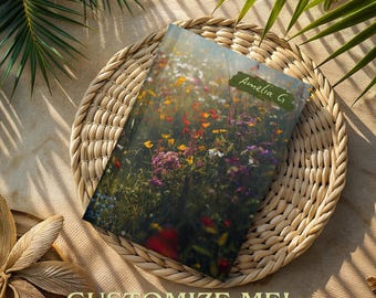 May include: A green, floral-patterned journal with the name "Amelia G" written on the cover. The journal is lying on a woven, circular placemat.