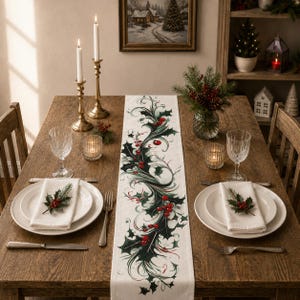 May include: A white table runner featuring a printed design of dark green holly leaves and bright red berries arranged in a flowing, central pattern. The runner is placed on a wooden table set with white plates, napkins, and glassware.