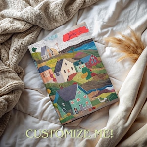 May include: A colorful illustrated notebook with a whimsical town scene featuring houses, trees, and a red sky. The cover reads "Julio L" in red lettering.