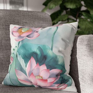 Peut inclure: Un coussin blanc avec un motif aquarelle de fleurs de lotus roses et de feuilles vertes.