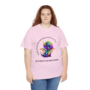 May include: Pink t-shirt with a colorful cartoon dragon and the text "People should stop expecting normal out of me. We all know it's not going to happen."