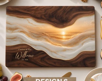 May include: A rectangular wooden serving board featuring a dark brown wood grain border and a central resin inlay depicting a sunset over the ocean with gold accents. The text Chelsea & Mac Williams Est. 2026 is printed in white script.