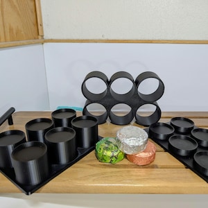 May include: A white ceramic mug with a black handle and the text "But First, Coffee" in a black, bold font. The mug is on a white surface. The mug is approximately 4 inches tall.