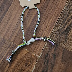 May include: A multi-colored braided bracelet with silver beads and a tag that says "Handmade with love".