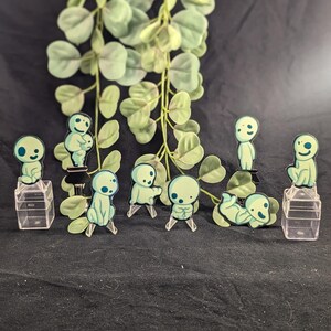May include: Eight green and blue cartoon characters on clear plastic stands. The characters are all different poses and are reminiscent of the characters from the movie "My Neighbor Totoro".