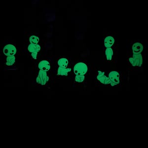May include: A set of nine glow-in-the-dark green figures, each with a unique pose and expression. The figures are small and appear to be made of a soft material.
