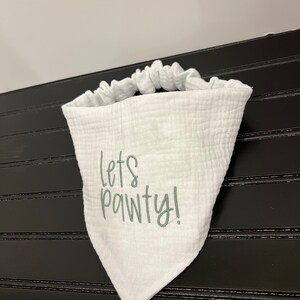 Pu&ograve; includere: Bandana bianca con un messaggio ricamato in verde che dice "Let's Pawty!"