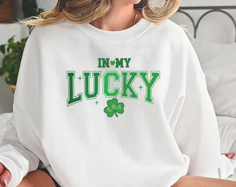 May include: White sweatshirt with green shamrock graphic and the text "In My Lucky Era".