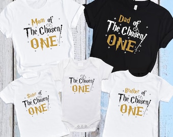 May include: Set of four white t-shirts with gold text and graphics. The shirts say "Mom of The Chosen One", "Dad of The Chosen One", "Sister of The Chosen One", and "Brother of The Chosen One".