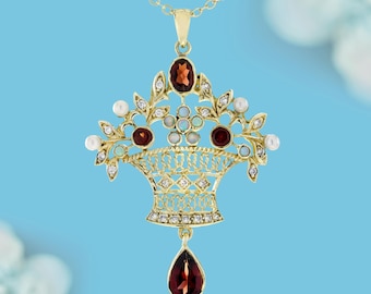 May include: A gold-toned pendant necklace featuring a basket design. The basket is adorned with red, white, and clear gemstones, and a teardrop-shaped red gemstone hangs below. The necklace has a delicate chain and is set against a blue background.