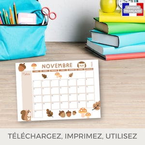 Puede incluir: Un calendario de noviembre de 2024 con fondo beige, con ilustraciones de bellotas, setas y una ardilla. El calendario est&aacute; sobre una superficie de madera, con una mochila azul y libros en el fondo. El texto "NOVEMBRE" es visible.