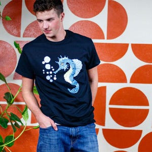 May include: A set of three ceramic mugs with a speckled, matte finish. The mugs are in shades of cream, light gray, and dark gray. Each mug has a simple, modern design and a rounded handle.