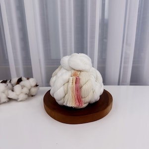 Pode incluir: Adereço de cabelo tradicional coreano branco com borlas rosa e brancas. O adereço de cabelo está em um suporte de madeira.