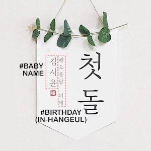 May include: A white banner with black text that reads "#BABY NAME" and "#BIRTHDAY (IN-HANGEUL)". The banner also features Korean text that reads "해오름달 이레 첫돌 시용 윤달 福".