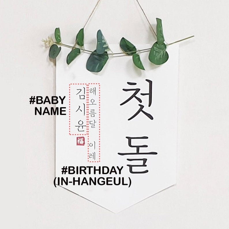 May include: A white banner with black text that reads "#BABY NAME" and "#BIRTHDAY (IN-HANGEUL)". The banner also features Korean text that reads "해오름달 이레 첫돌 시용 윤달 福".