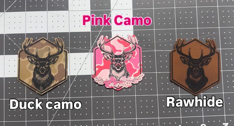 May include: Three decorative patches with deer designs. One features a deer head on a duck camo background, another on a pink camo background, and the last on a rawhide background. The text "Pink Camo", "Duck camo", and "Rawhide" are displayed.
