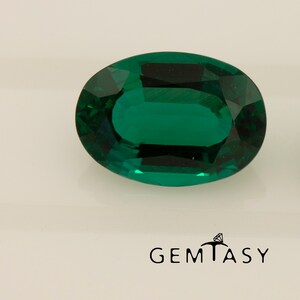 May include: A vibrant green oval-shaped gemstone with a faceted cut. The gemstone is set against a white background.