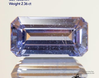 May include: A rectangular, light blue sapphire gemstone with a cornflower hue. The gem is 10x5mm and weighs 2.36 ct. The image includes the text "Grown Sapphire Cornflower Light" and "GEMTASY".