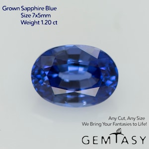 May include: An oval-cut, grown sapphire gemstone in a deep blue hue. The gem measures 7x5mm and weighs 1.20 ct. Text on the image reads "Grown Sapphire Blue, Size 7x5mm, Weight 1.20 ct" and "Any Cut, Any Size, We Bring Your Fantasies to Life!" with the Gemtasy logo.