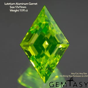 May include: A vibrant, lime-green Lutetium Aluminum Garnet gemstone with a diamond cut. The gem is 17x11mm and weighs 11.91 ct. The image includes the text "Any Cut, Any Size" and "We Bring Your Fantasies to Life!" with the Gemtasy logo.