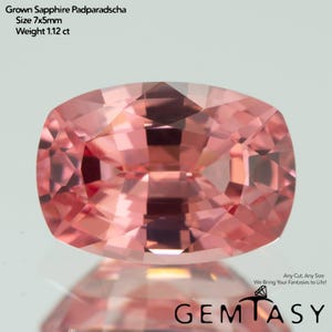 May include: A cushion-cut, pink-orange Padparadscha sapphire gemstone. The gem is 7x5mm in size and weighs 1.12 carats. The image includes the text "Grown Sapphire Padparadscha", "Size 7x5mm", and "Weight 1.12 ct". The Gemtasy logo is in the bottom right corner.