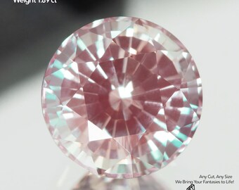 May include: A faceted, lab-grown alexandrite gemstone. The round-cut stone is a light pink color with hints of teal and measures 7mm in size and weighs 1.89 carats. The image includes the text "GEMTASY".