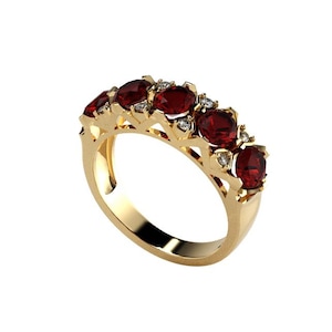 Könnte beinhalten: Ein goldener Ring mit fünf ovalen, tiefroten Edelsteinen. Kleine, klare Akzentsteine sind zwischen den größeren Edelsteinen gesetzt. Der Ring hat ein durchbrochenes Design am Band, und der Gesamtstil ist elegant und klassisch.